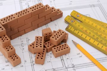 Mattoncini, matita e metro su foglio di carta che riproduce una planimetria