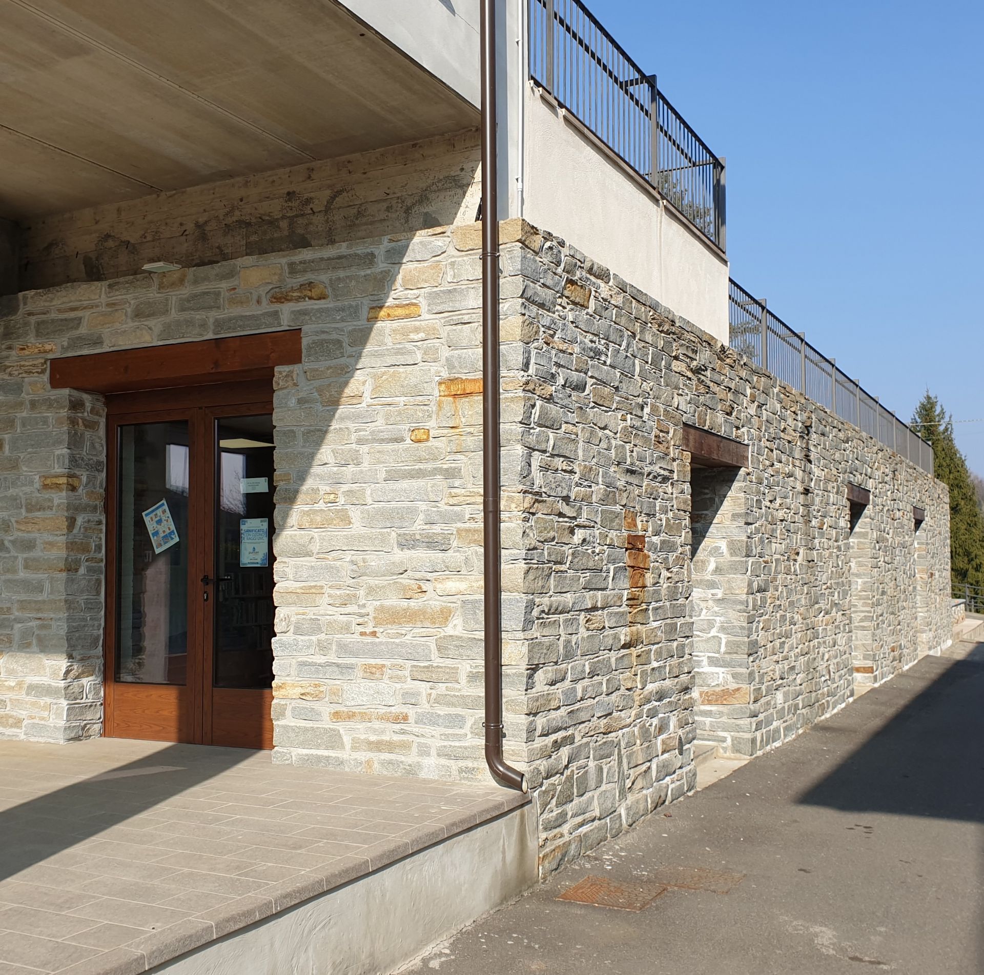 Veduta esterna della Biblioteca comunale con muri in pietra e porta di accesso